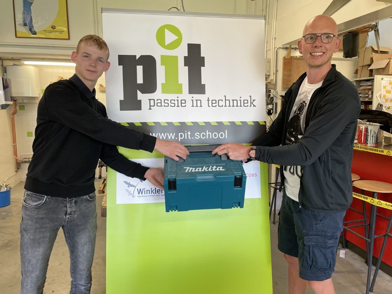 docent Rick overhandigt leerling Raymond de boormachine van Makita