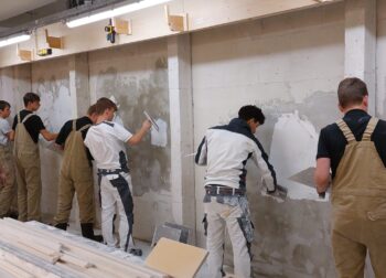 leerlingen oefenen met stukadoren van een muur