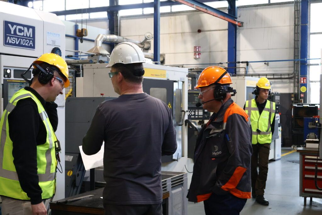 Medewerker van Hydro geeft uitleg over een machine